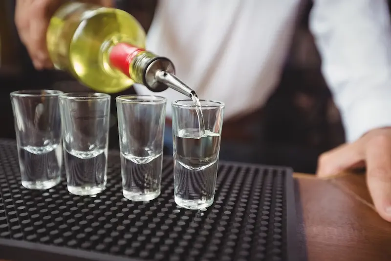 primer-plano-de-barman-vertiendo-pisco-en-vasos
