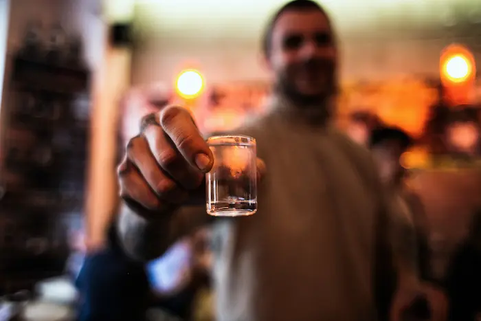 persona con un shot de pisco en la mano