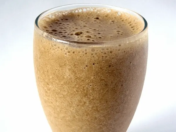 Proceso de preparación de malta con leche en vaso grande con espuma