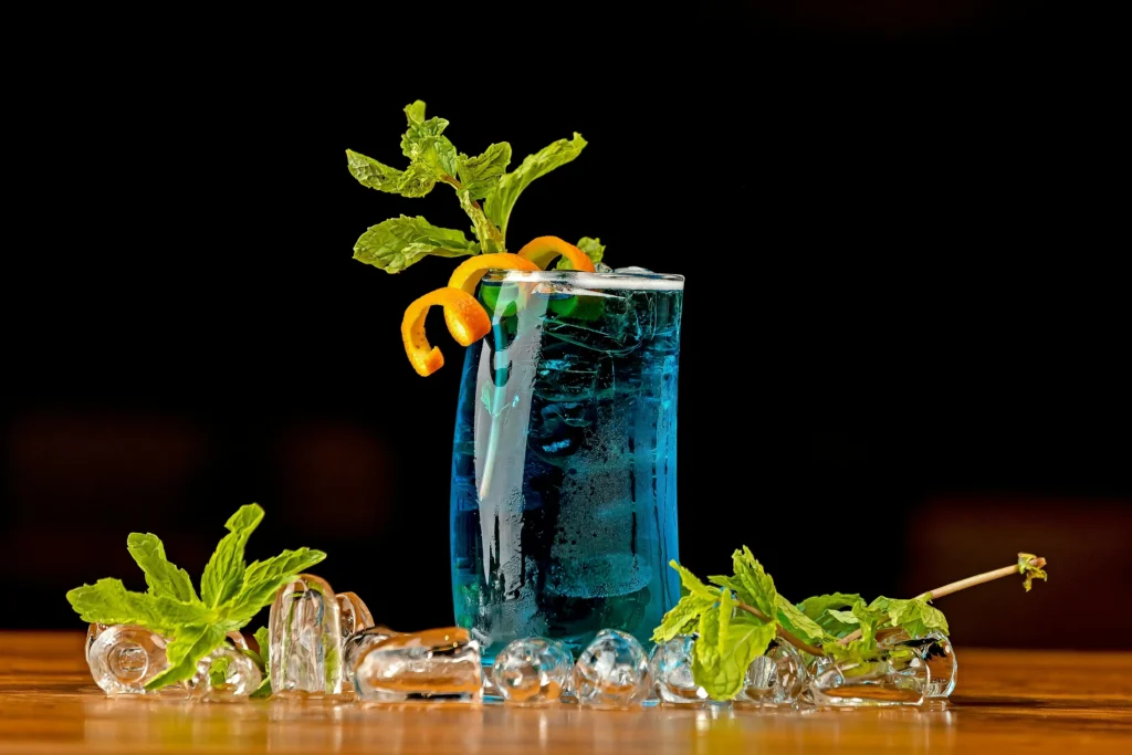 Cóctel Long Island Blue en vaso alto con decoración sobre fondo oscuro
