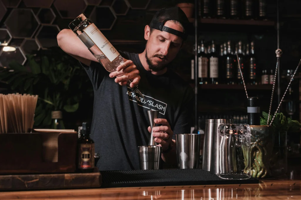 Bartender preparando cóctel Long Island Blue mezclando licores en barra