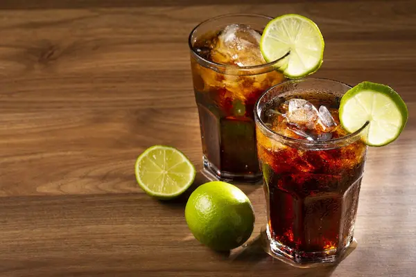 Copa de trago Cuba Libre con hielo y limón, introducción al cóctel